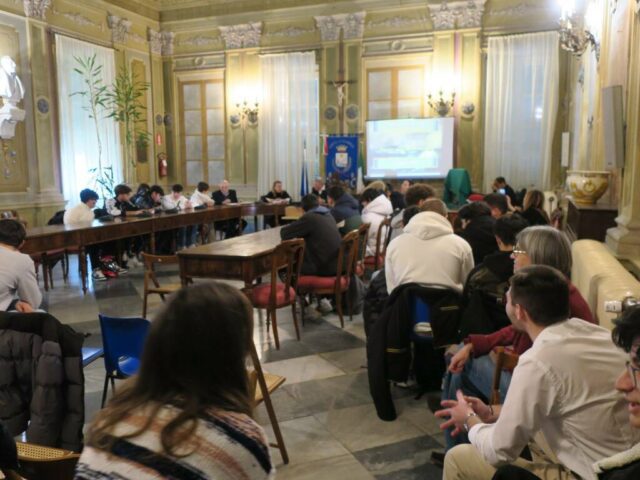 Camogli, Istituto Nautico si evolve il progetto “Giovani al centro” Il nuovo ciclo di incontri del progetto “Giovani al centro” voluto da Claudio Pompei, consigliere comunale con delega alle politiche giovanili, sport e tempo libero ha preso avvio questa mattina 22 gennaio 2024, nella Sala Consiliare del Comune di Camogli. Questo è il quarto incontro o per meglio dire laboratorio didattico ideato e realizzato dalla Prof. ssa Marta Riotti in collaborazione con il com.te Bruno Malatesta, membro e rappresentante della Società Capitani e Macchinisti Navali di Camogli. Il progetto è rivolto agli studenti delle classi 5CN e 5CNA dell’Istituto Nautico San Giorgio con sede in Camogli. • «E’ un piacere per il Comune aprire le porte ed ospitarvi. Lo scopo è quello di creare una sinergia nuova col mondo della scuola. Siamo qui anche per ascoltarvi, sentire le vostre idee, esigenze, problematiche. – Ha spiegato Pompei nella presentazione dell’ incontro. – Sono anch’io padre e quindi penso di conoscere ansie ed aspettative dei giovani della vostra età. Parlatecene». Il programma prevede gli interventi dei relatori Prof.ssa Riotti, dell’Istituto Nautico San Giorgio sede di Camogli e del com.te Malatesta. Durante la presentazione gli studenti hanno illustrato un loro elaborato per poi rispondere alle domande che i presenti hanno posto. La spiegazione dell’elaborato, il dibattito sono la realizzazione del progetto di comunicazione e discussione tra gli alunni. L’intero incontro è visibile sul sito del Comune di Camogli e sulla pagina Facebook del dott. Claudio Pompei Consigliere comunale. Camogli, Istituto Nautico si evolve il progetto “Giovani al centro”